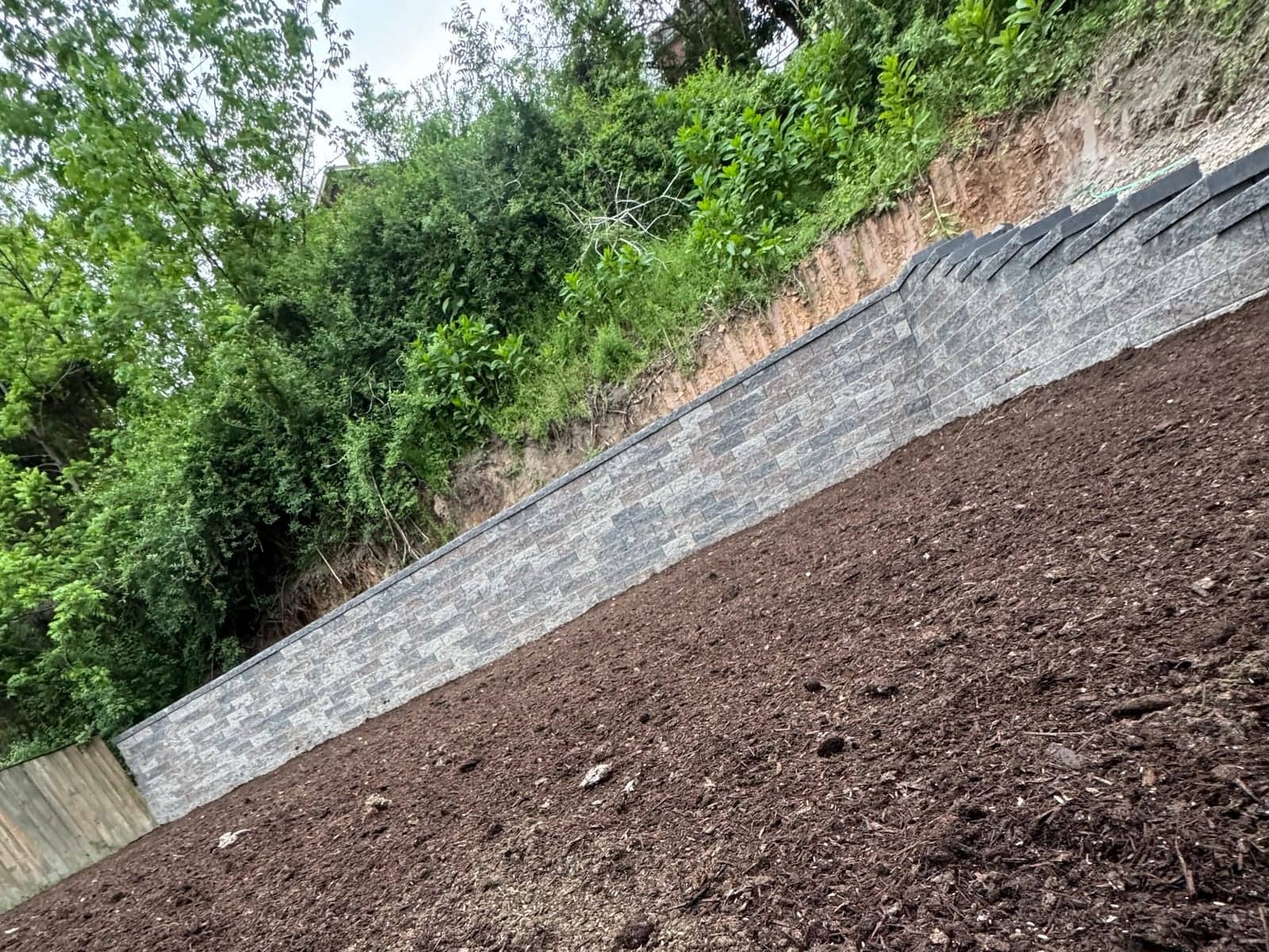 Hillside excavation alongside a retaining wall for exterior drainage in Pittsburgh