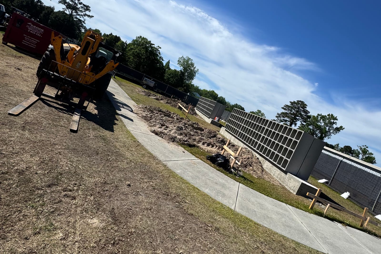 Precast concrete open-grid wall units set on a cast base with a telehandler on site
